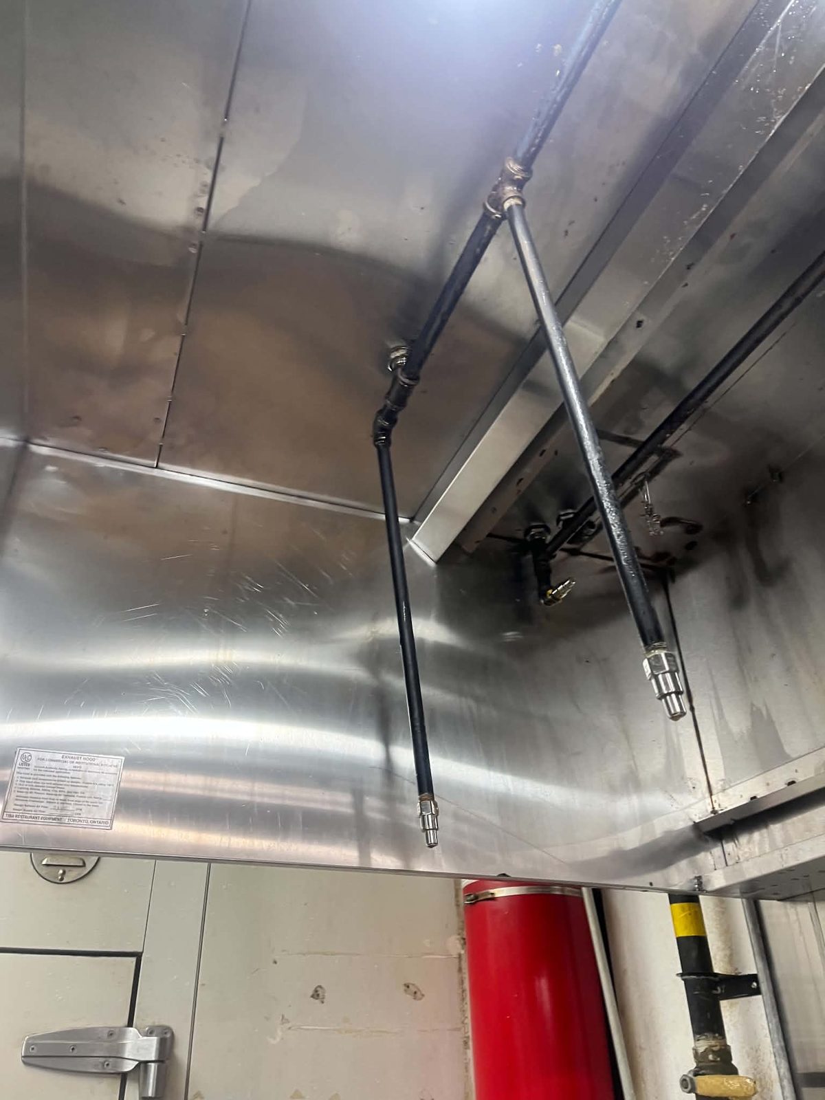 The same kitchen exhaust system cleaned to bare metal — Same hood, same visit. The suppression tank and nozzles on the right are in both frames.